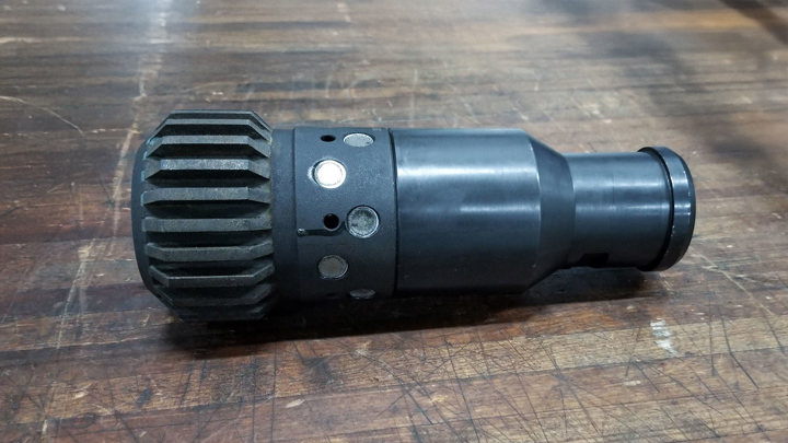 Welltec E-line milling tool used to enable ceramic screen installation in a Trinidad gas well, placed on a wooden surface pre-deployment.