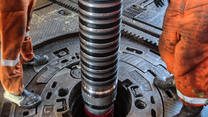 Steam rises from a geothermal hot spring surrounded by colorful mineral deposits and forested hills, illustrating natural geothermal energy.